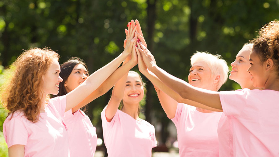 Women high fiving in Breast Cancer Awarenes Month