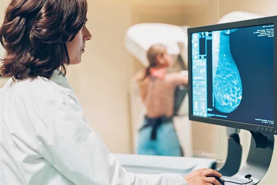 radiologist performing mammogram on patient